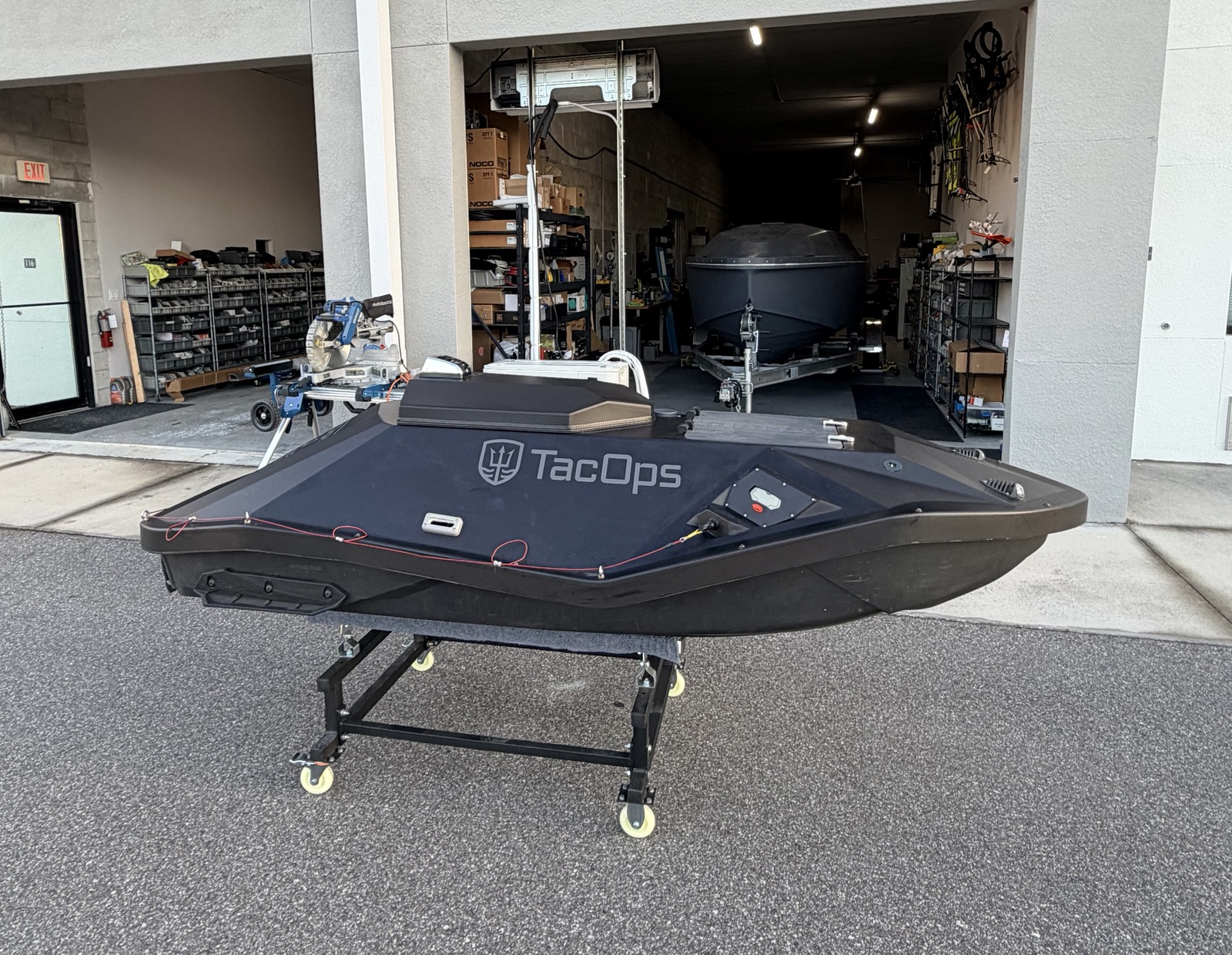 TacOps TOMS-9 compact unmanned surface vessel on a support dolly inside a TacOps workshop bay